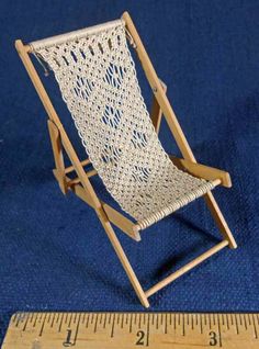 a miniature chair sitting next to a ruler on a blue cloth background, with the scale in front of it