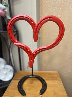 a pair of scissors shaped like a heart on top of a wooden table next to a vase