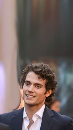 a young man in a suit and tie smiles at the camera as he stands outside