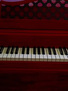 a red piano with white and black keys sitting in front of a purple background,