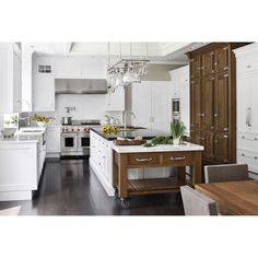 a kitchen with white cabinets and an island in front of a stove top oven next to a dining room table