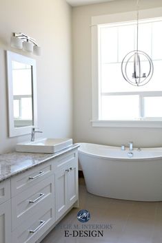 a white bath tub sitting under a bathroom window next to a sink and counter top