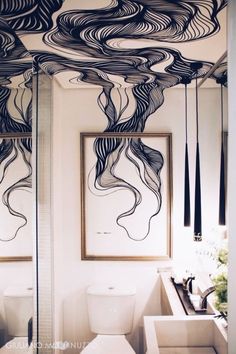 a bathroom with black and white artwork on the ceiling