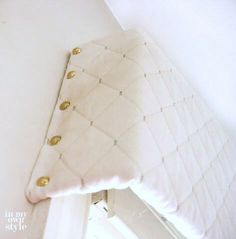 a white pillow sitting on top of a bed next to a wall mounted light fixture