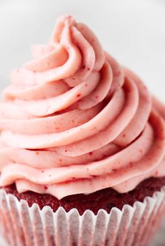 a cupcake with pink frosting sitting on top of a white plate