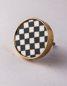 a black and white checkerboard design ring on a white surface with gold trim