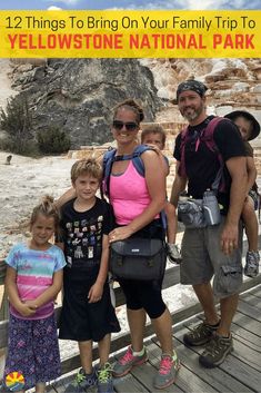 three adults and two children standing on a boardwalk in front of a geyser