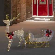 two lighted reindeer sleighs in front of a red door