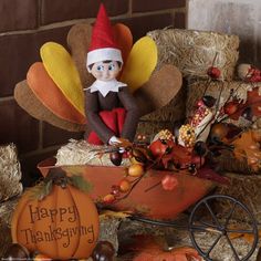 an elf sitting on top of a pumpkin next to a wagon filled with autumn leaves