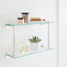 two glass shelves holding various items in the bathroom, one shelf has a brush and toothbrush on it