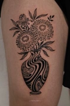 a black and white vase with flowers in it on someone's thigh or leg