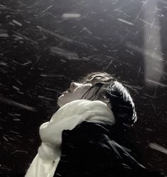 a woman standing in the snow with her head down and an umbrella over her shoulder