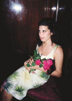 a woman sitting on a chair with flowers in her hand