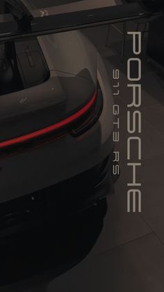 the back end of a black sports car on display at a showroom with an advertisement for porsche