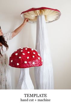 a girl is holding up a paper mache mushroom