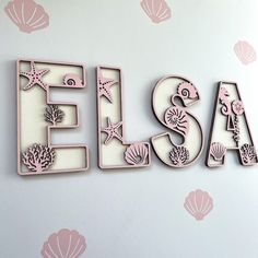 the word sea spelled with cutouts and seashells on a white wallpapered background