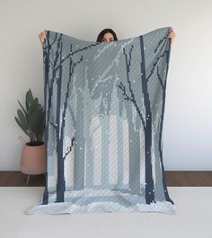 a woman is holding up a blanket with trees on it