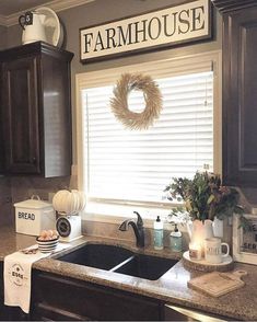 a kitchen sink under a window with a sign on the wall above it that says farmhouse