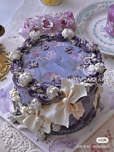 there is a purple cake with white flowers on the plate next to other plates and dishes