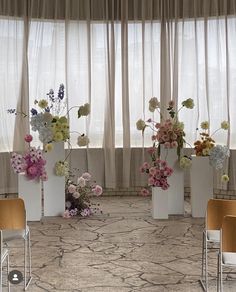 four white vases filled with different types of flowers on a carpeted room floor