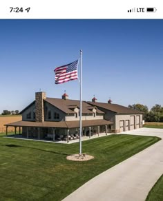 an american flag is flying in front of a large house with a driveway leading to it