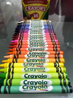 many crayons are lined up on a table with a carton in the background