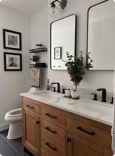 a bathroom with double sinks and mirrors above it's countertop, along with pictures on the wall