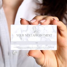 a woman holding up a business card that says your next appointment