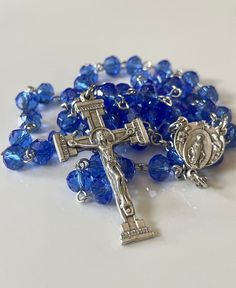 This handmade rosary has 8x6mm blue faceted glass beads. The crucifix and rosary center are antique silver finished.  While some Catholics sometimes wear their rosaries around their necks for safekeeping and easy access to their prayer beads, this is not built for the purpose of being worn. I do offer rosary bracelets if you are looking for a rosary you can wear.  Please be sure to read all shop policies before placing your order. Thank you!  ** I do not offer gift wrapping or gift messaging. Pl Silver Faceted Beads Rosary Cross, Blue Rosary With 8mm Beads And Crucifix, Blue Rosary With 8mm Beads In Cross Shape, Rosary With Faceted Beads And Crucifix, Object Collection, Blue Rosary, Handmade Rosary, Rosary Bracelet, Writing Gifts