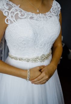 a woman in a white dress is holding her hand on her waist and wearing a gold belt