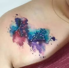 a woman's chest with a colorful tattoo on it and stars in the sky