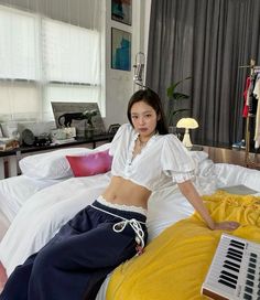 a woman sitting on top of a bed next to a yellow comforter and pillows