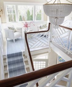 an overhead view of a staircase leading to a living room with white furniture and chandelier