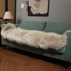 a living room with a green couch and white fur rug on the floor next to a lamp