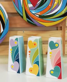 three colorful vases sitting next to each other on top of a white countertop