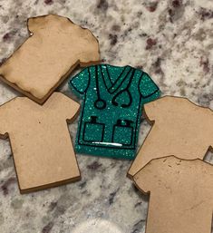 three cut out pieces of paper with clothes on them sitting on a marble counter top