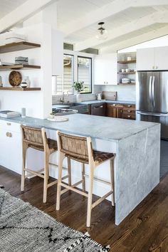 a kitchen with two stools next to an island