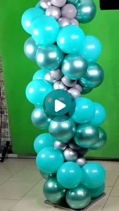 a bunch of blue and silver balloons are stacked on top of each other in front of a green wall