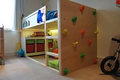 a child's bedroom with a climbing wall and toy bins on the floor