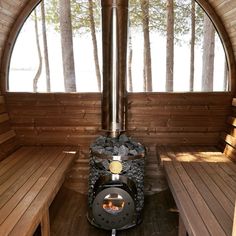 the inside of a wooden cabin with benches and a fire place in it's center