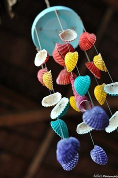 a colorful wind chime with shells hanging from it's sides and hearts attached to the strings