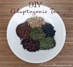 a white plate topped with lots of different types of dry tea on top of a wooden table