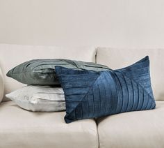 two pillows sitting on top of a white couch