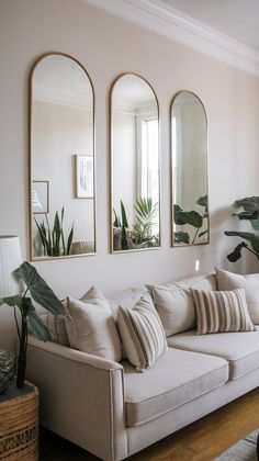 a living room with three mirrors on the wall and two couches in front of them