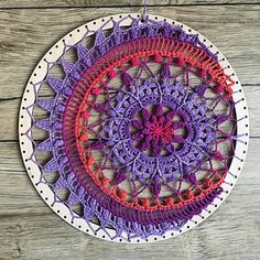 a crocheted doily hanging on a wooden wall with purple and red accents