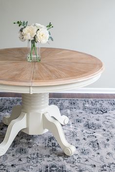 a vase with flowers sitting on top of a wooden table in front of a rug