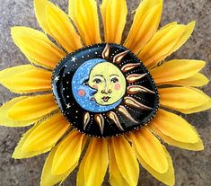 a sunflower with a face painted on it's center and the moon in the middle