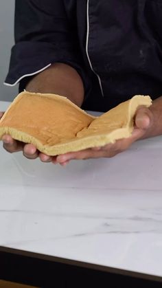 a person holding a piece of bread on top of a counter