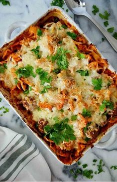 a casserole dish with meat, cheese and parsley on the side next to a fork