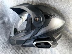 a close up of a motorcycle helmet on a gray surface with the visor partially closed